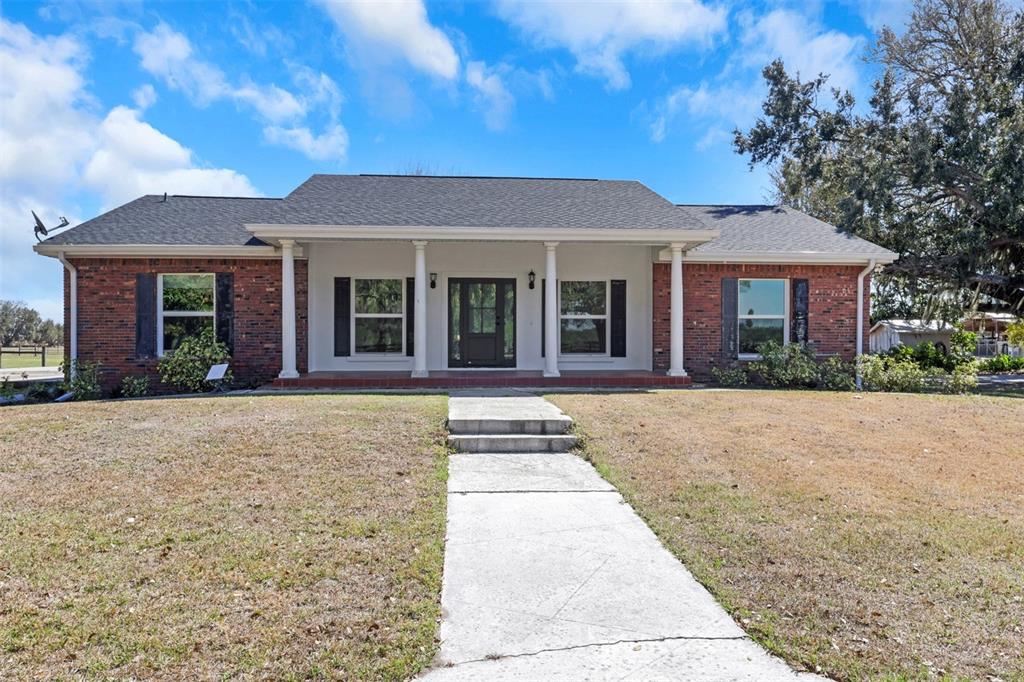 A single-story brick house features a covered front porch with white columns and black shutters — 3597 SE CO RD 760 ROAD UNIT 760, ARCADIA, FL