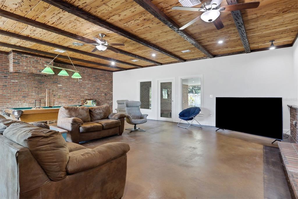 A spacious living room features a brick wall, wood-plank ceiling with beams, and concrete floors — 3597 SE CO RD 760 ROAD UNIT 760, ARCADIA, FL