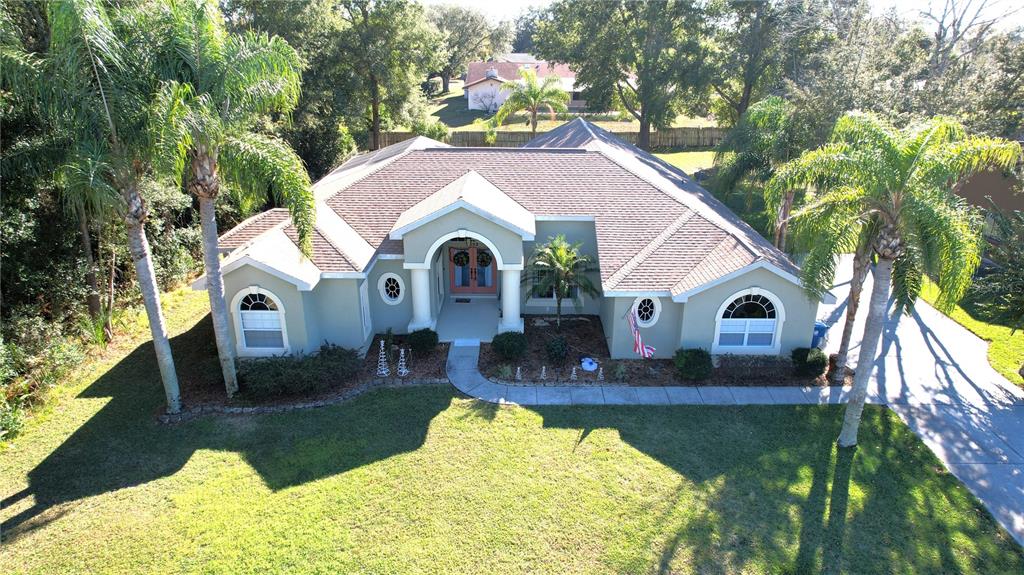 An aerial view of a single-story house with a light green exterior and palm trees — 7552 RIVER COUNTRY DRIVE, WEEKI WACHEE, FL