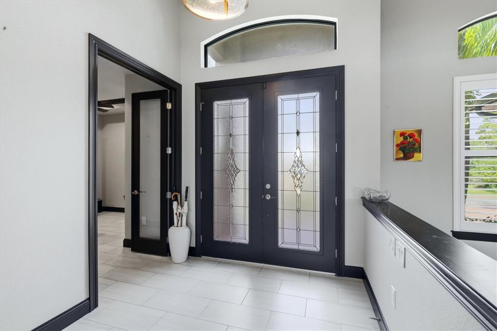 An entryway features dark double doors with glass inserts, tile flooring, and a transom window — 9404 SPRING CIRCLE, PORT CHARLOTTE, FL
