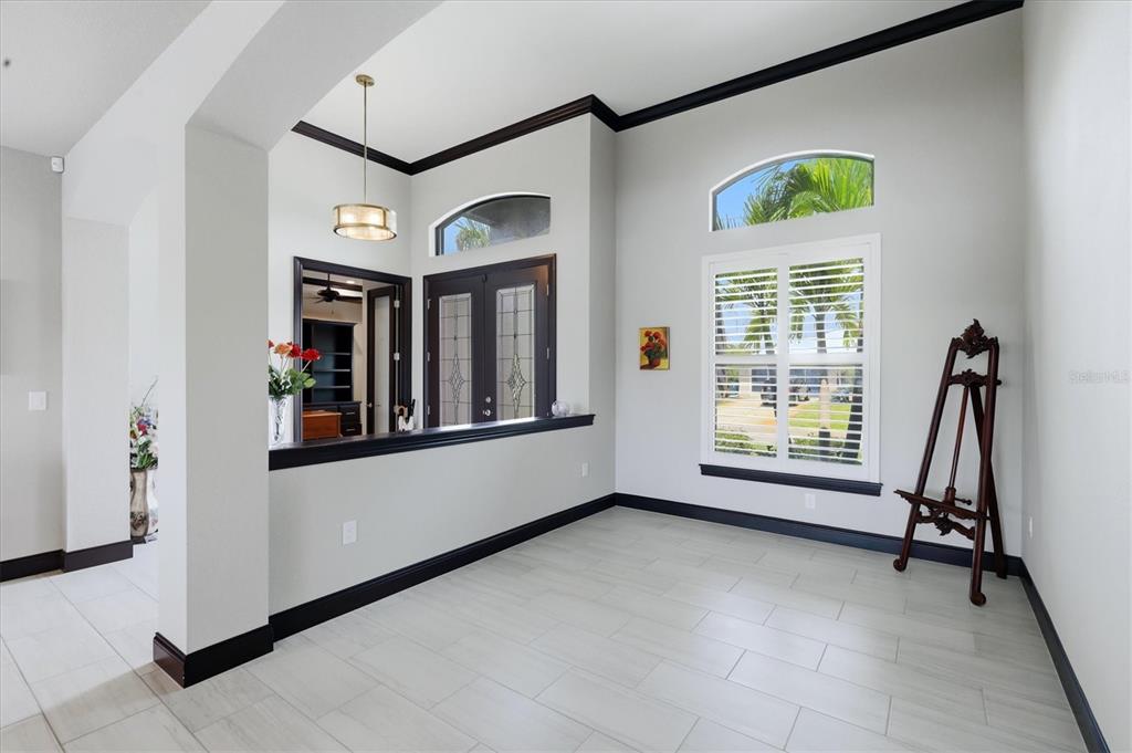 A bright room features light tile flooring, dark trim, a wooden easel, and arched windows — 9404 SPRING CIRCLE, PORT CHARLOTTE, FL