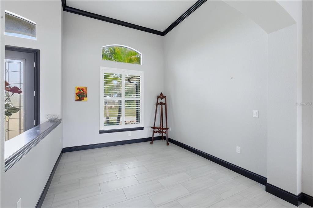 A room with light gray tile flooring, white walls, black trim, and a wooden easel — 9404 SPRING CIRCLE, PORT CHARLOTTE, FL