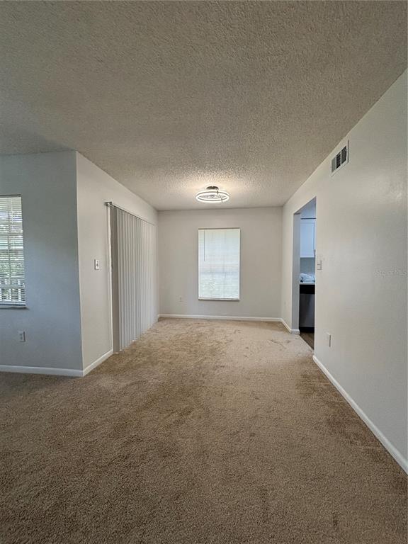 An empty dining area features beige carpeting, a central light fixture, and vertical window blinds — 2690 CORAL LANDINGS BOULEVARD UNIT 615, PALM HARBOR, FL