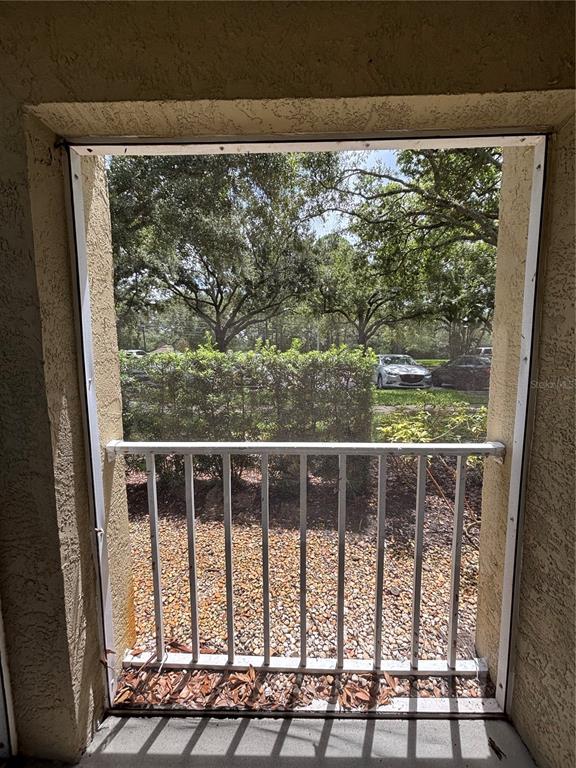 A view from a screened-in balcony looking out toward a parking lot and trees — 2690 CORAL LANDINGS BOULEVARD UNIT 615, PALM HARBOR, FL