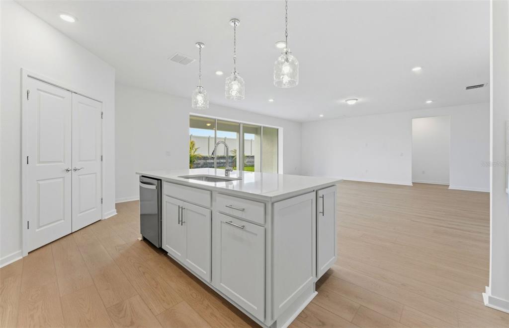 A kitchen island with a sink and pendant lights sits in an open-concept room — 9738 AUTUMN RIDGE AVENUE, RIVERVIEW, FL