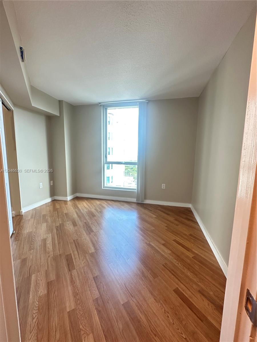 An empty room features light-colored walls, wood-look flooring, and a single window with blinds — 9066 SW 73rd Ct # 1903, Miami FL 33156, MIAMI, FL