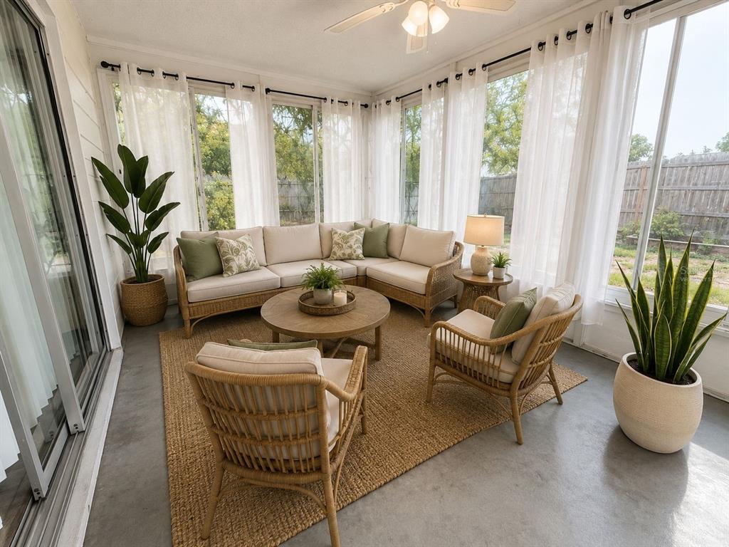 A sunroom features a wicker sectional, two armchairs, a round coffee table, and concrete floors — 9129 SEWELL LANE, SPRING HILL, FL
