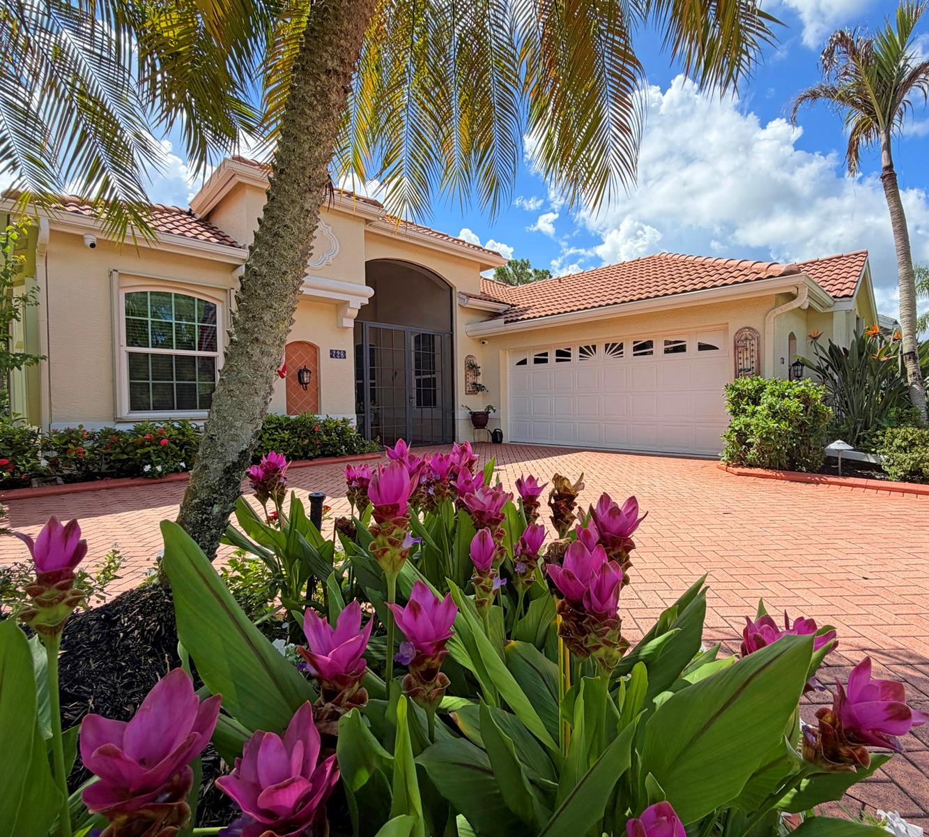 A single-story house with a tiled roof, garage, and pink flowers in the foreground — 728 SW Lake Charles Circle, Port St. Lucie FL 34986, PORT ST. LUCIE, FL