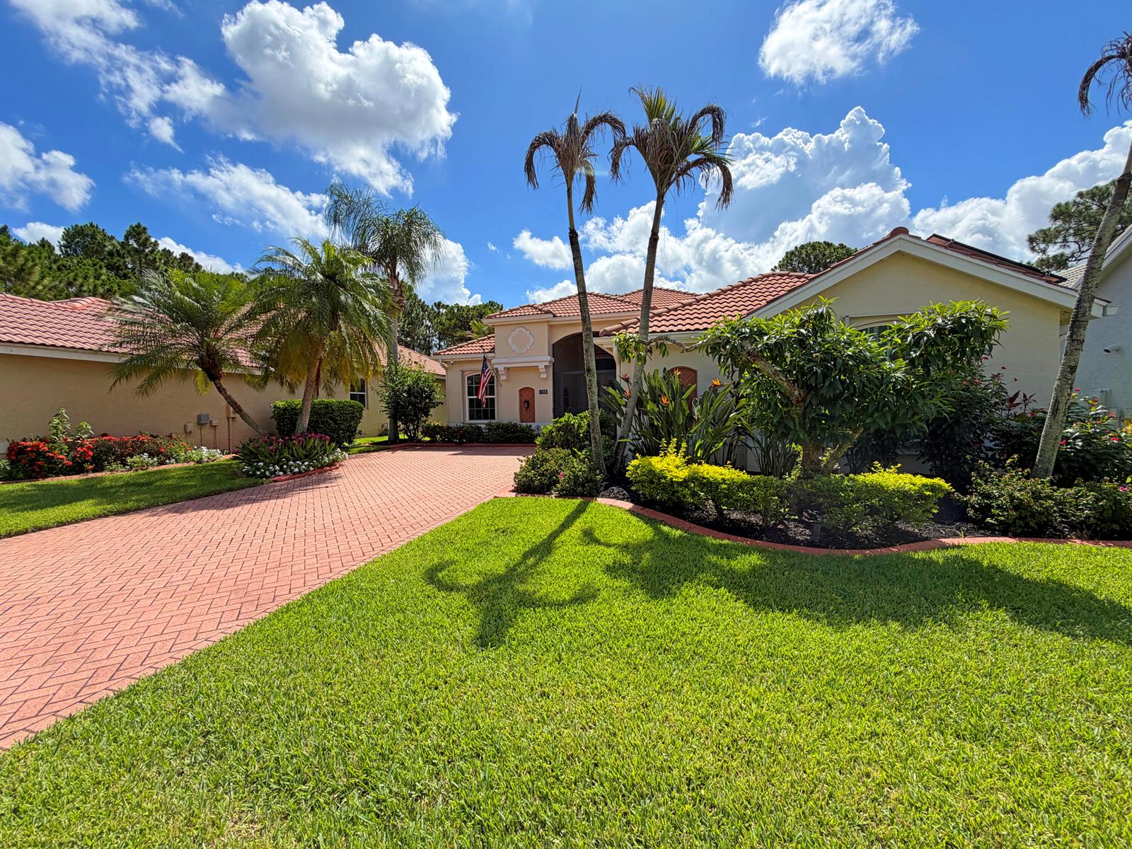 A single-story house with a red tile roof and a paved driveway under a blue sky — 728 SW Lake Charles Circle, Port St. Lucie FL 34986, PORT ST. LUCIE, FL