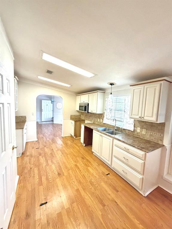 A kitchen with white cabinets, wood flooring, and a pass-through to an adjacent room — 3217 NW 64TH STREET, COCONUT CREEK, FL