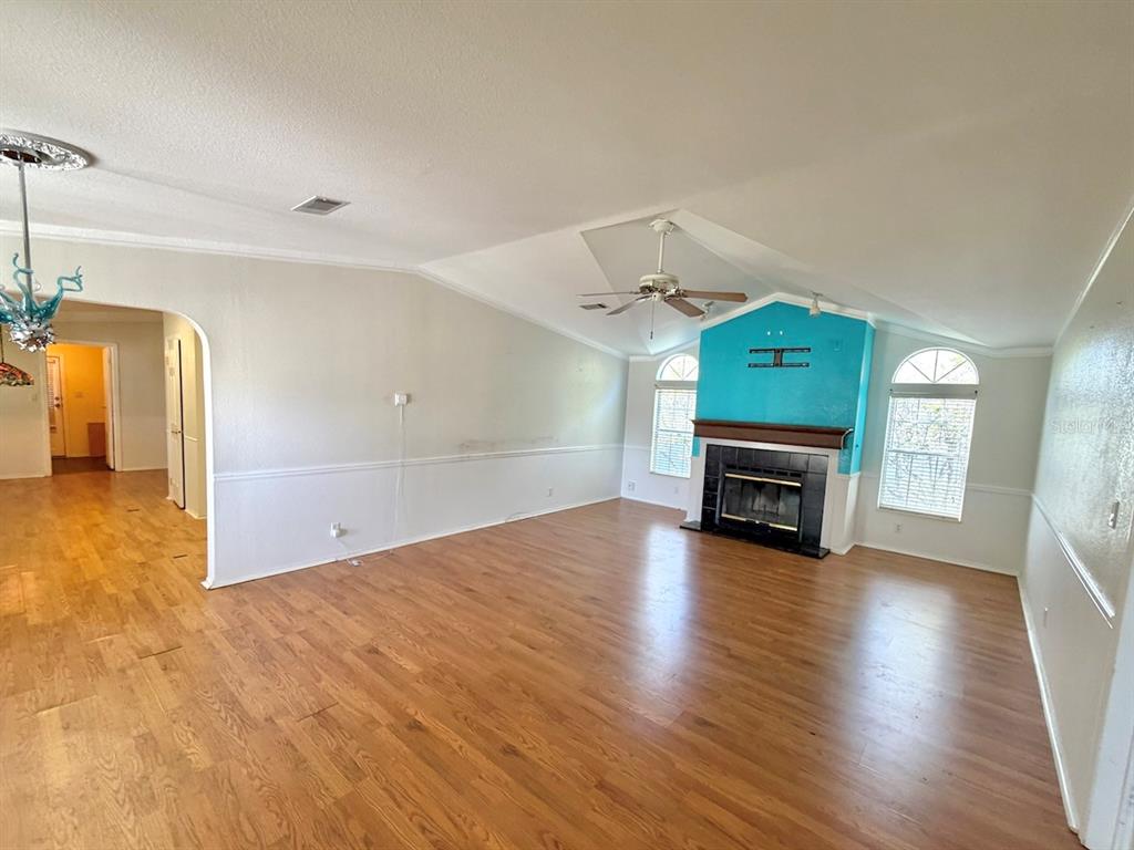 A living room with hardwood floors, a vaulted ceiling, and a teal fireplace accent wall — 3217 NW 64TH STREET, COCONUT CREEK, FL