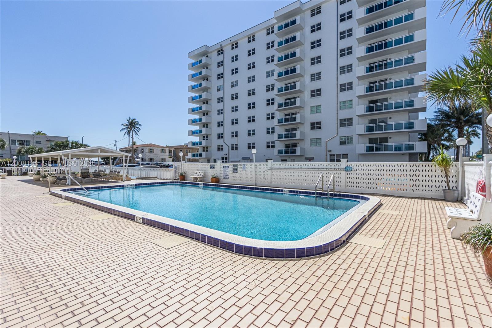 A rectangular swimming pool sits on a brick patio in front of a tall apartment building — 1601 S Ocean Dr # 305, Hollywood FL 33019, HOLLYWOOD, FL