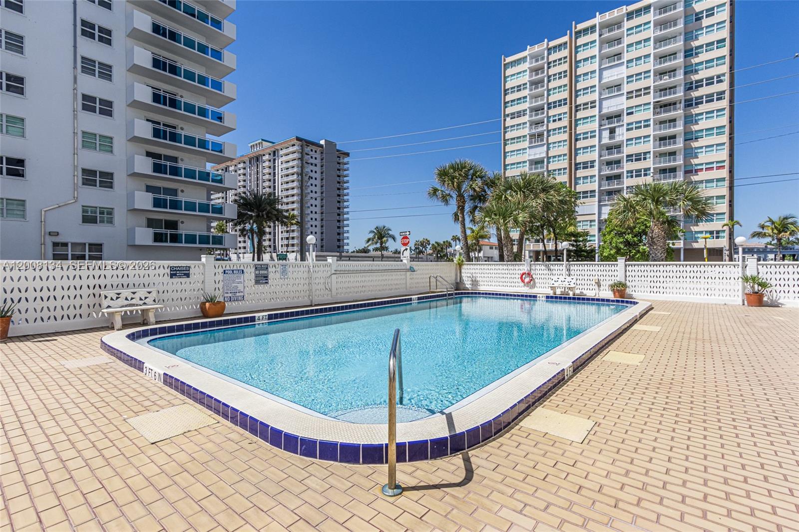 A rectangular outdoor swimming pool is surrounded by a paved deck and tall apartment buildings — 1601 S Ocean Dr # 305, Hollywood FL 33019, HOLLYWOOD, FL