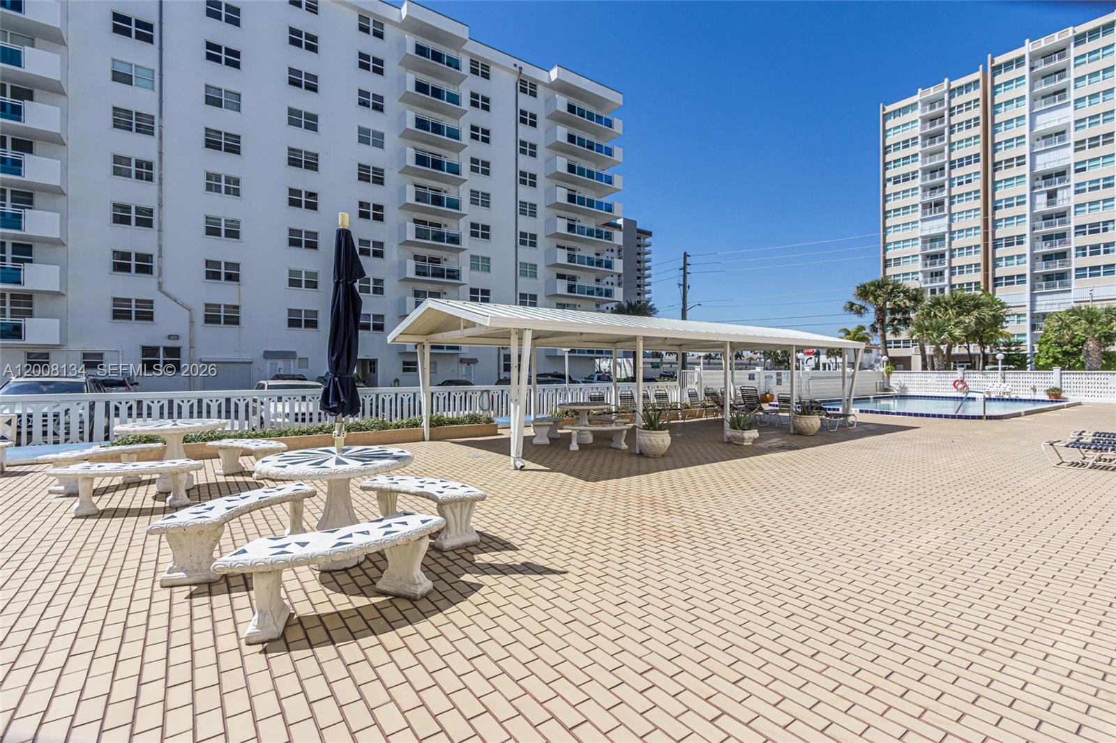 An outdoor pool deck features a covered patio area, stone tables, and high-rise buildings — 1601 S Ocean Dr # 305, Hollywood FL 33019, HOLLYWOOD, FL