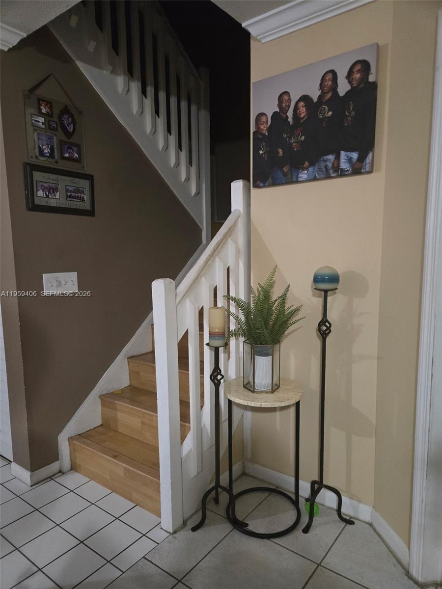A staircase with wooden steps and a white railing stands next to a small table — 4925 W Lakes Dr, Deerfield Beach FL 33442, DEERFIELD BEACH, FL