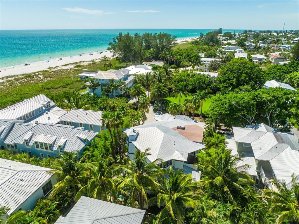 An aerial view shows several coastal homes with metal roofs surrounded by lush tropical trees — 103 PARK AVENUE, ANNA MARIA, FL