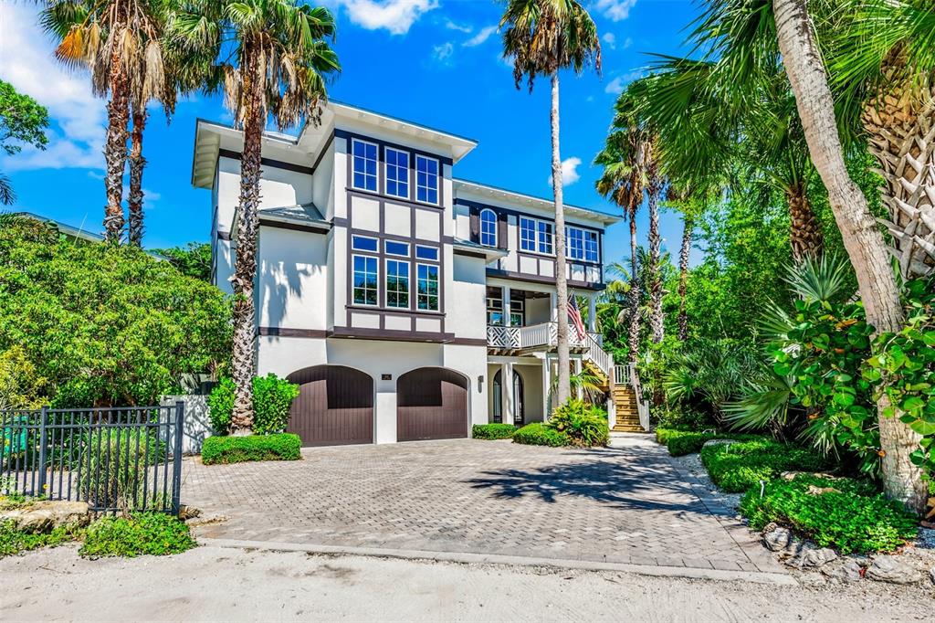 A three-story white house with dark trim, a paved driveway, and palm trees — 103 PARK AVENUE, ANNA MARIA, FL