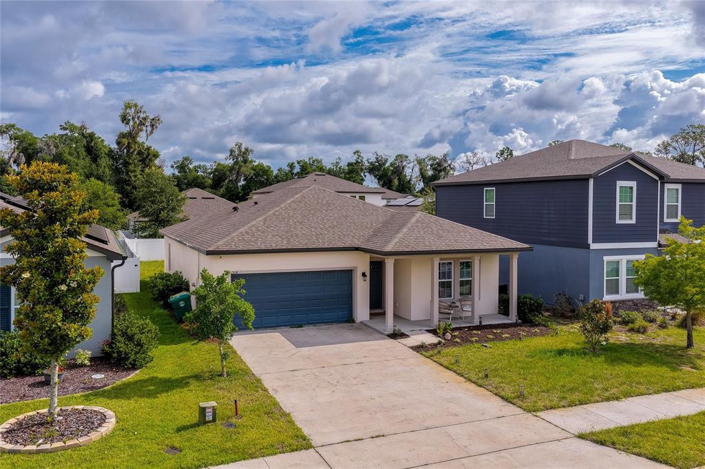A single-story house with a blue garage and a covered front porch under a cloudy sky — 1514 PLAYWRIGHT DRIVE, DELAND, FL