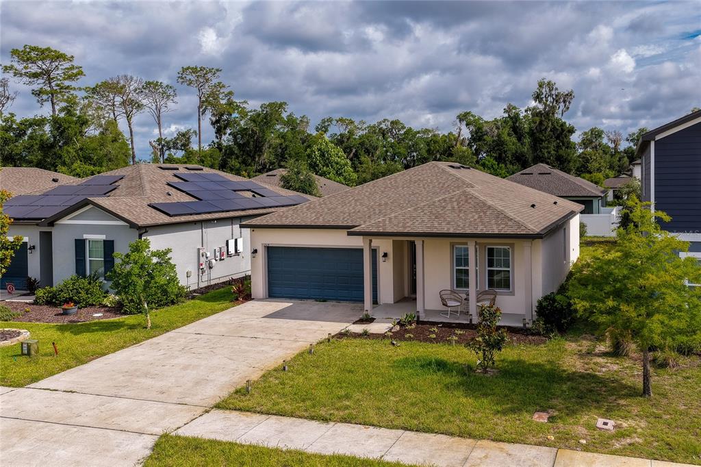 A single-story suburban house with a blue garage door and a covered front porch — 1514 PLAYWRIGHT DRIVE, DELAND, FL