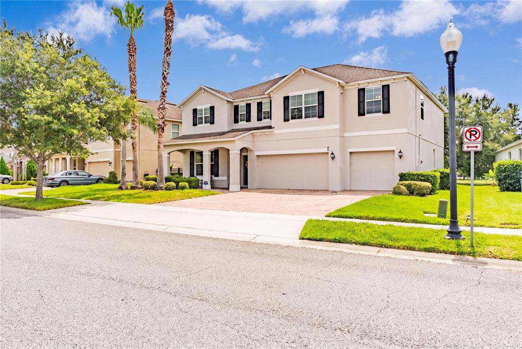 A two-story suburban house features a beige stucco exterior, a three-car garage, and palm trees — 12225 STONE BARK TRAIL, ORLANDO, FL