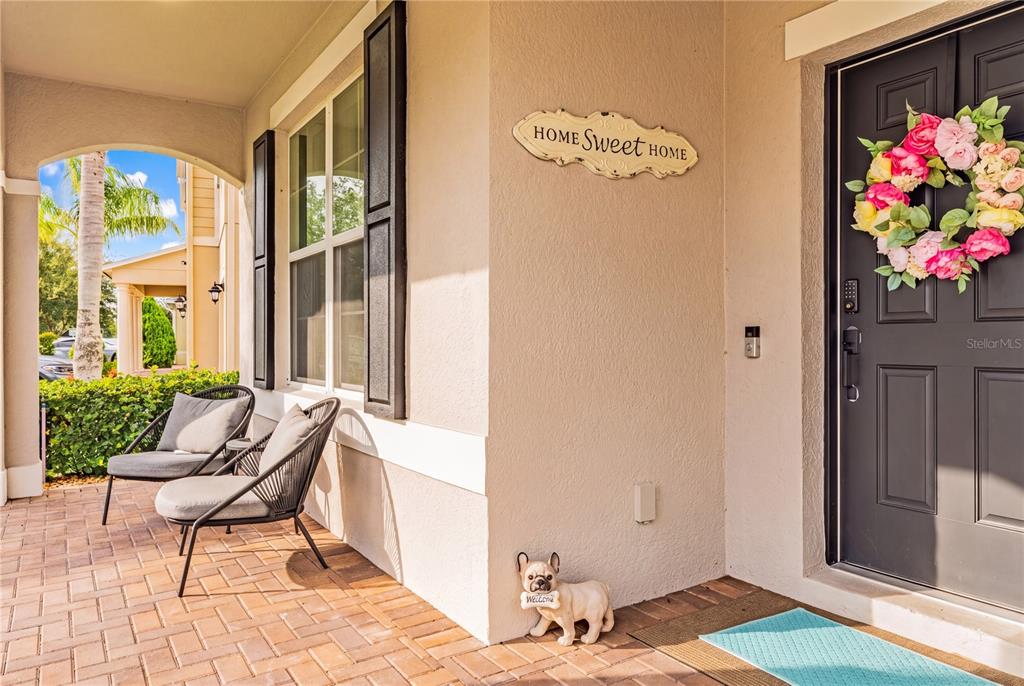 A covered front porch features two chairs, a decorative sign, and a small dog statue — 12225 STONE BARK TRAIL, ORLANDO, FL