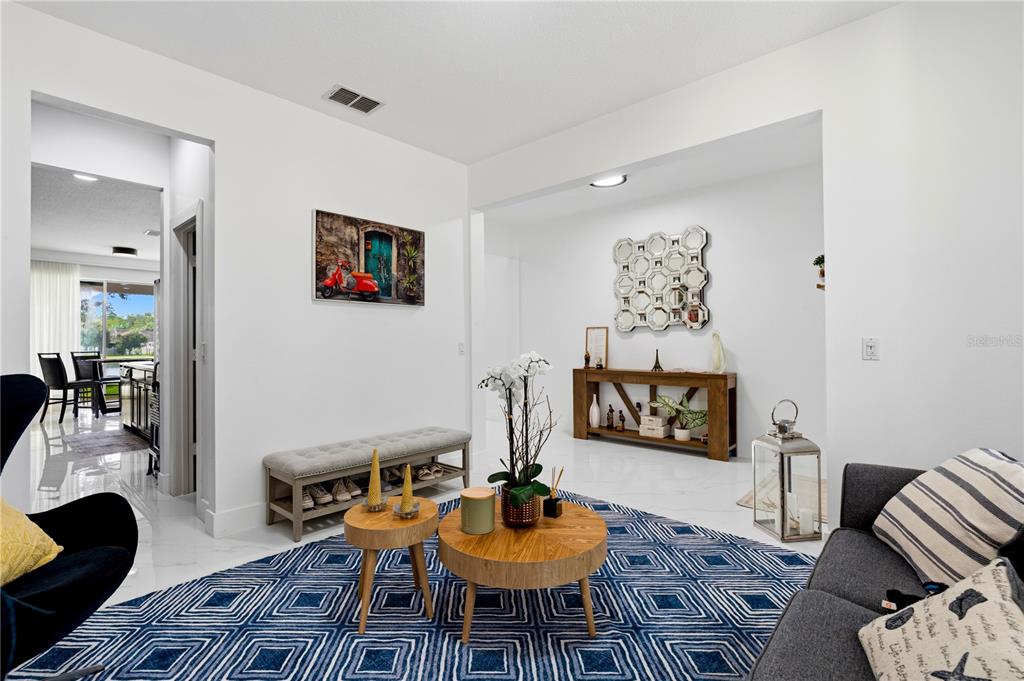 A living room features a blue geometric rug, a wooden console table, and a bench — 12225 STONE BARK TRAIL, ORLANDO, FL
