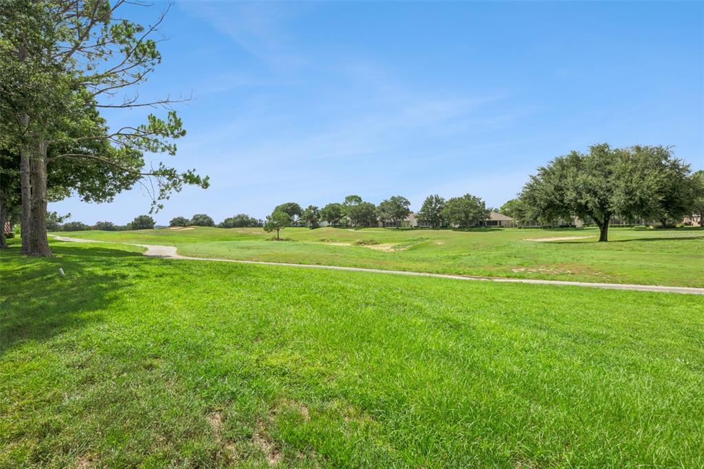 A view of a grassy golf course fairway with trees and houses in the distance — 2284 ADDISON AVENUE, CLERMONT, FL