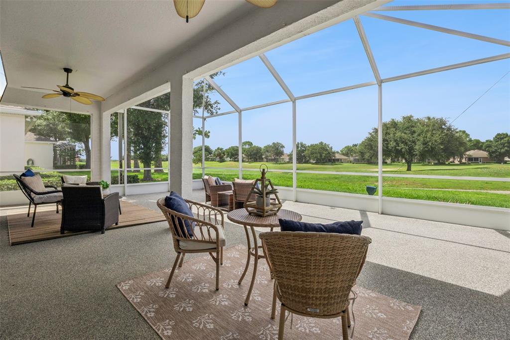 The rear exterior of a house features a screened-in lanai and a large grassy yard — 2284 ADDISON AVENUE, CLERMONT, FL