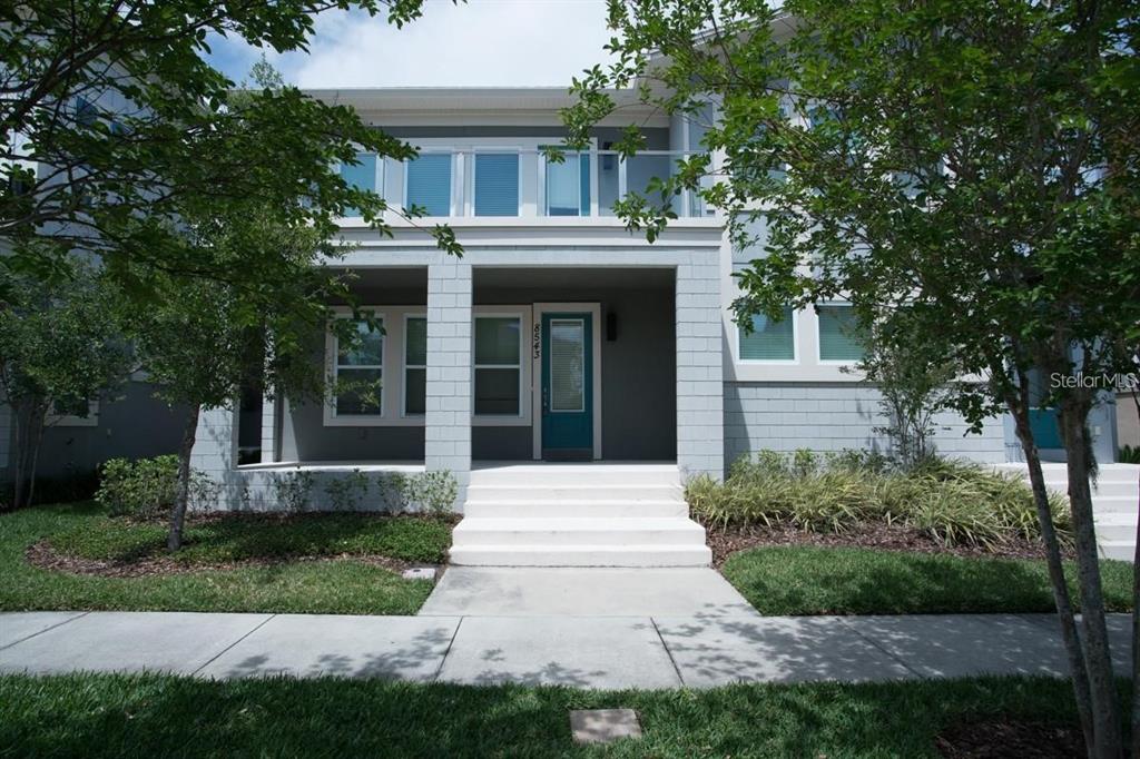 A two-story house with a covered front porch, white steps, and a teal front door — 8543 PINTER STREET, ORLANDO, FL