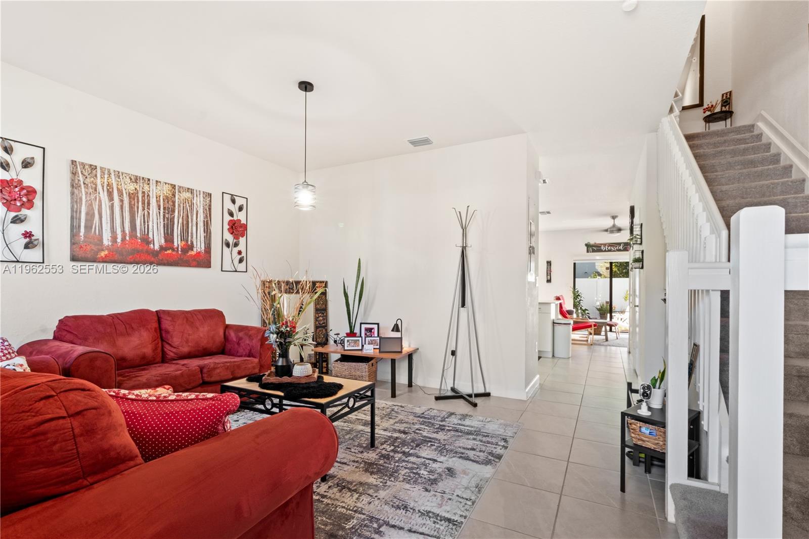 A living room features red sofas, a patterned area rug, and a staircase — 11438 W 34th Ct, Hialeah FL 33018, HIALEAH, FL