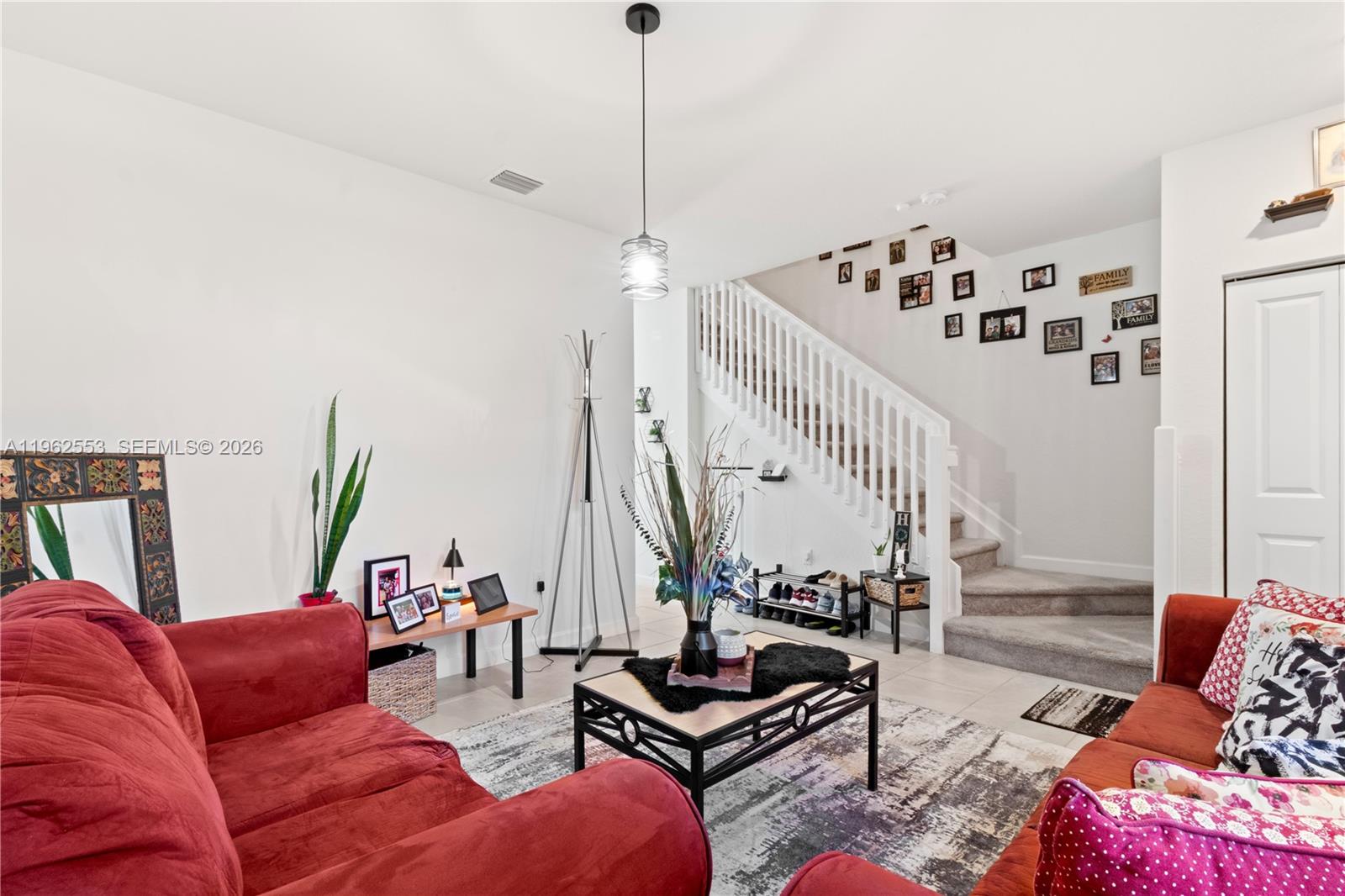 A living room features red sofas, a coffee table, and a staircase with a gallery wall — 11438 W 34th Ct, Hialeah FL 33018, HIALEAH, FL