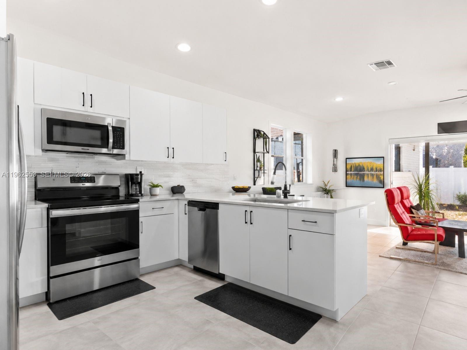 A modern kitchen features white cabinets, stainless steel appliances, and a central island — 11438 W 34th Ct, Hialeah FL 33018, HIALEAH, FL