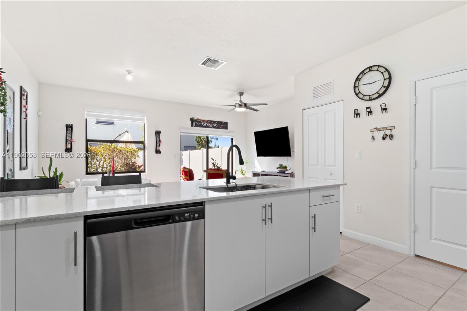 A modern kitchen features a white island with a stainless steel dishwasher and sink — 11438 W 34th Ct, Hialeah FL 33018, HIALEAH, FL
