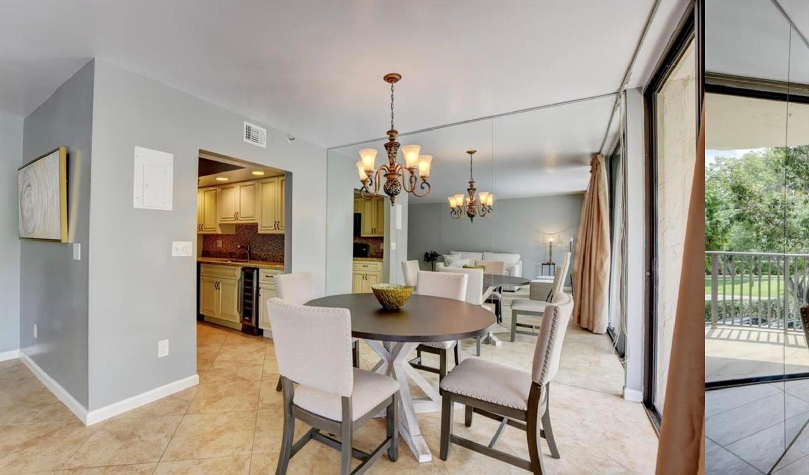 A dining area with a round table, chandelier, and mirrored wall next to a kitchen — 859 Jeffery Street # 3030, Boca Raton FL 33487, BOCA RATON, FL