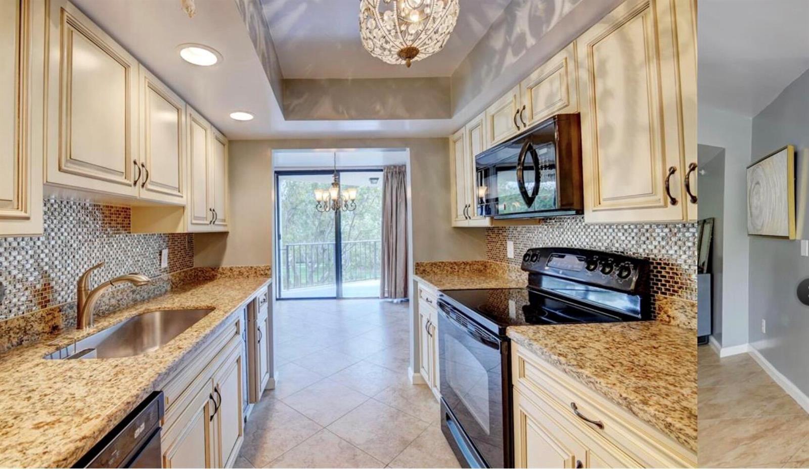 A galley kitchen features cream cabinets, granite countertops, a mosaic backsplash, and stainless steel appliances — 859 Jeffery Street # 3030, Boca Raton FL 33487, BOCA RATON, FL