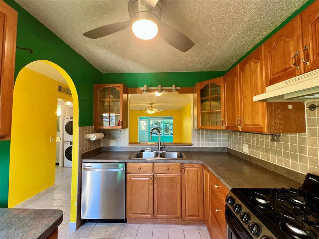 A kitchen with wood cabinets, stainless steel appliances, and a pass-through window to another room — 2971 MISSION DRIVE E UNIT 54F, CLEARWATER, FL
