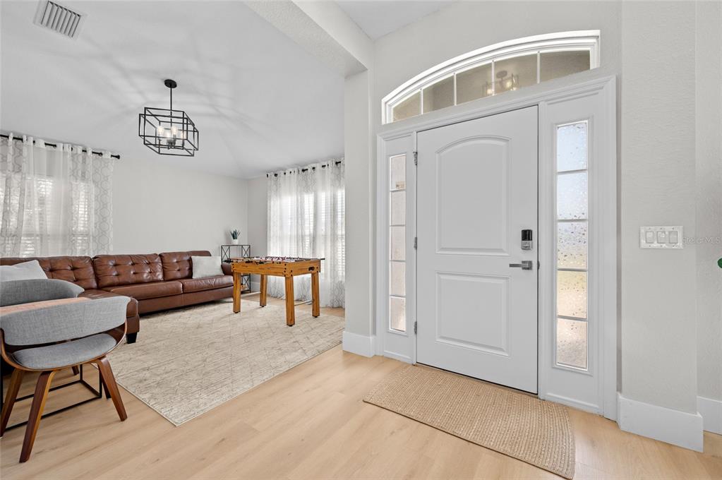 An entryway leads into a living area featuring a brown leather sofa and foosball table — 17 WHITE MARSH LANE, ROTONDA WEST, FL