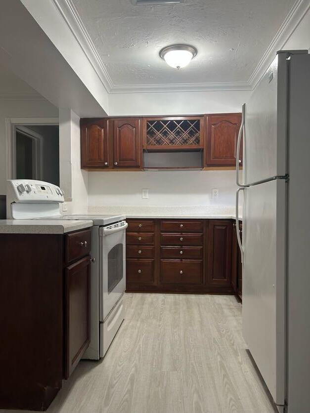 A kitchen features dark wood cabinets, white appliances, light countertops, and light wood-look flooring — 3920 7th Avenue N, FL 33461, FL