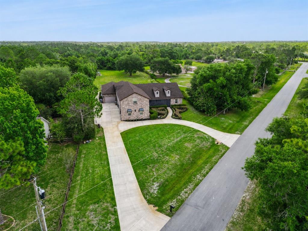 An aerial view shows a brick house with a circular driveway surrounded by trees — 2075 MUSTANG COURT, ST CLOUD, FL
