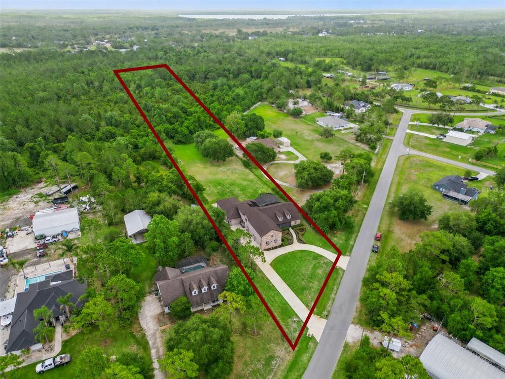 An aerial view shows a large house on a long, narrow lot with wooded areas — 2075 MUSTANG COURT, ST CLOUD, FL