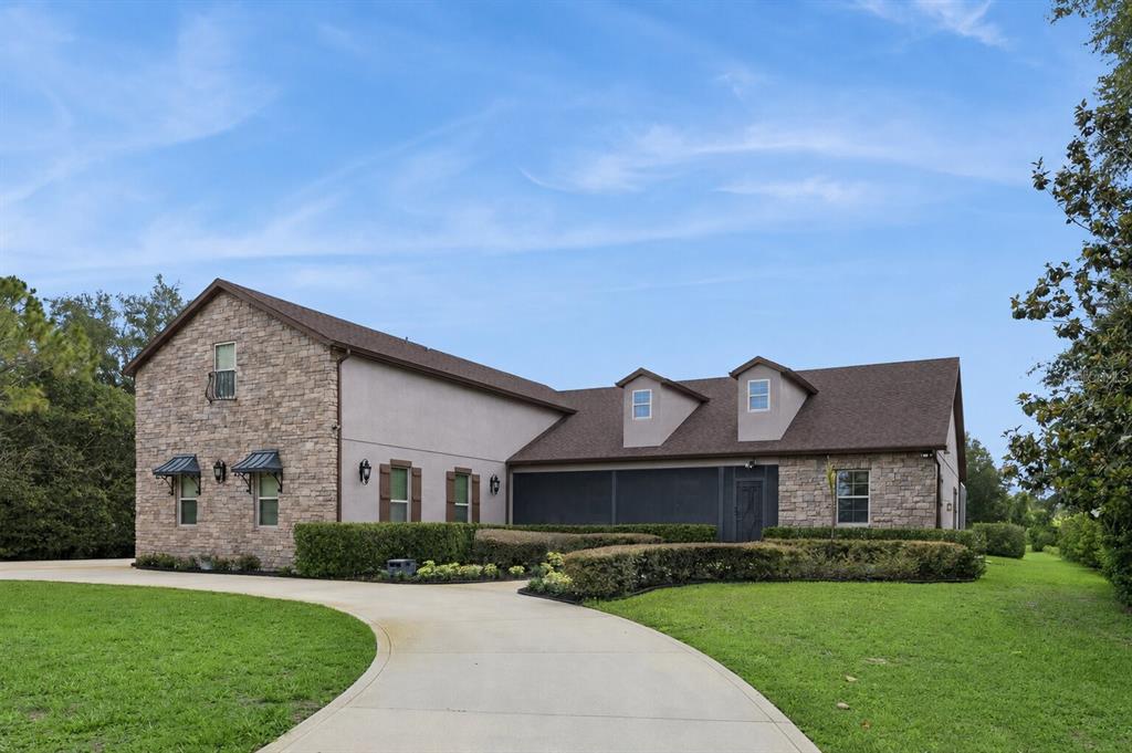 A two-story house with stone veneer, a brown roof, and a curved concrete driveway — 2075 MUSTANG COURT, ST CLOUD, FL