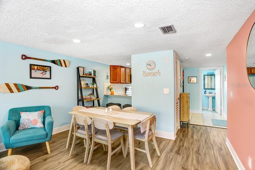 A dining area with a light wood table, chairs, and a blue accent wall — 314 WINDRUSH BOULEVARD UNIT 12, INDIAN ROCKS BEACH, FL