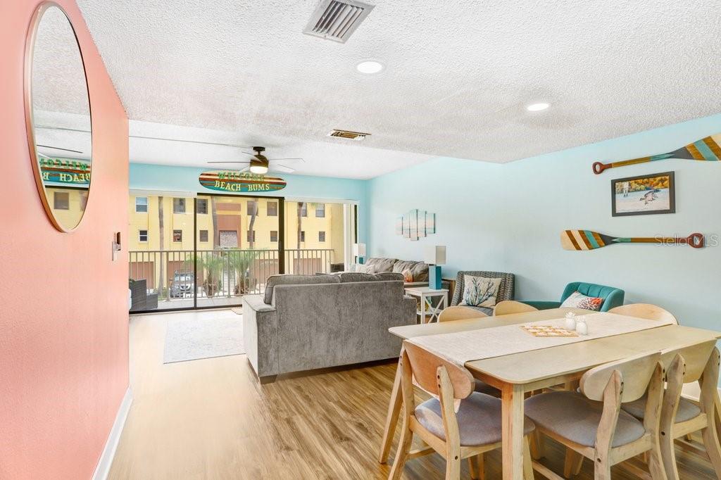 A living and dining area features light blue walls, wood-look flooring, and a sliding glass door — 314 WINDRUSH BOULEVARD UNIT 12, INDIAN ROCKS BEACH, FL