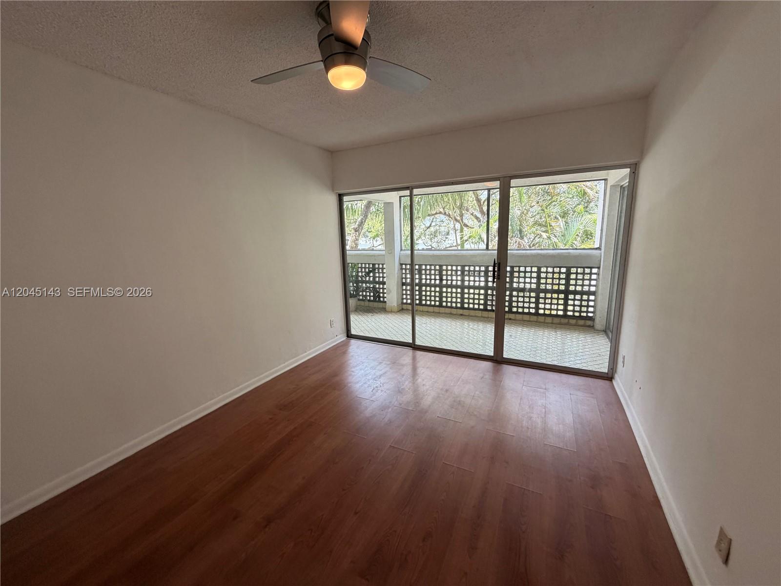 An empty room with wood-look flooring, a ceiling fan, and sliding glass doors to a balcony — 3301 Spanish Moss Ter # 306, Lauderhill FL 33319, LAUDERHILL, FL