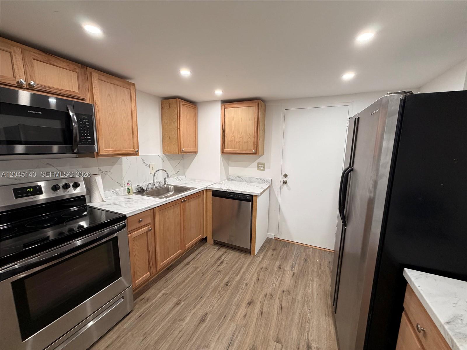 A kitchen features wood cabinets, stainless steel appliances, and white marble-patterned countertops — 3301 Spanish Moss Ter # 306, Lauderhill FL 33319, LAUDERHILL, FL