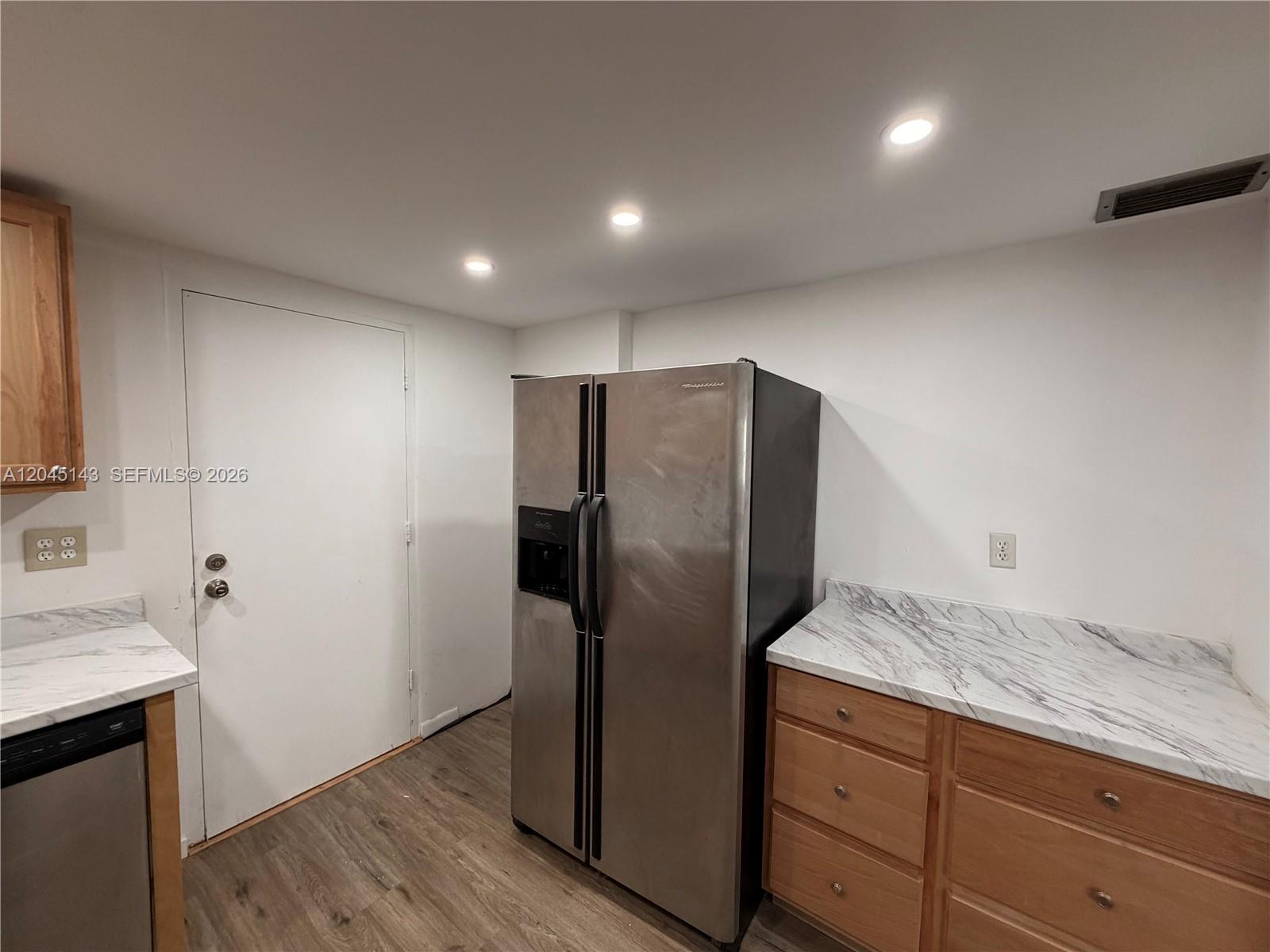 A kitchen features a stainless steel refrigerator, wood cabinets, and white marble-patterned countertops — 3301 Spanish Moss Ter # 306, Lauderhill FL 33319, LAUDERHILL, FL