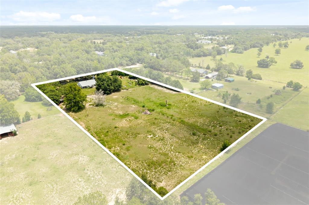 An aerial view shows a large, rectangular plot of land with a house and trees — 35819 NOVA LANE, EUSTIS, FL