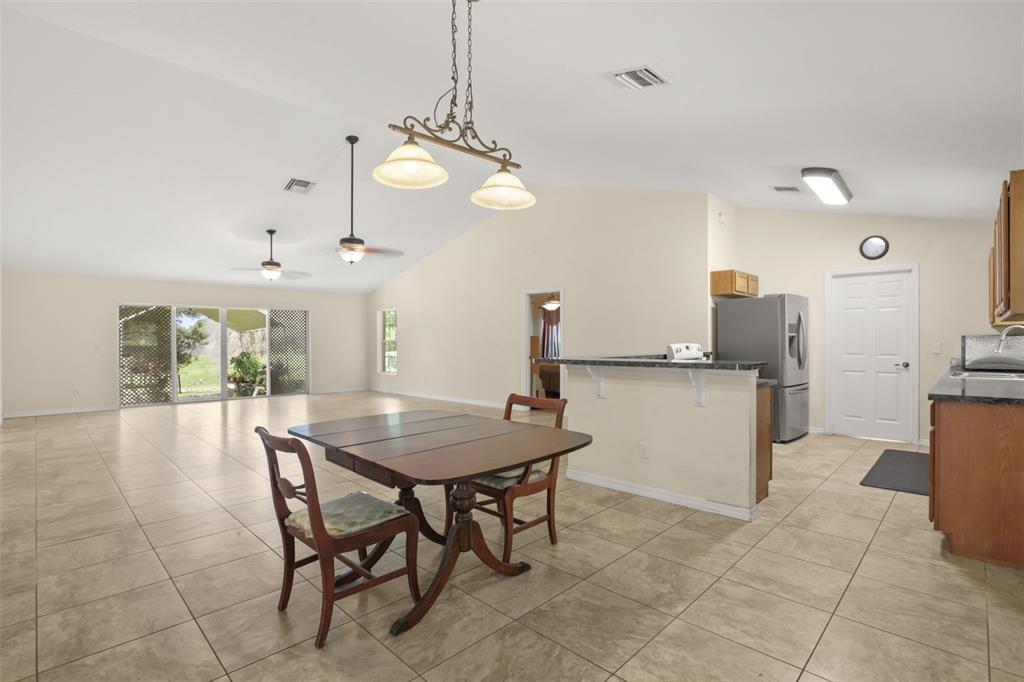 A dining area with a wooden table and chairs sits next to an open kitchen — 35819 NOVA LANE, EUSTIS, FL