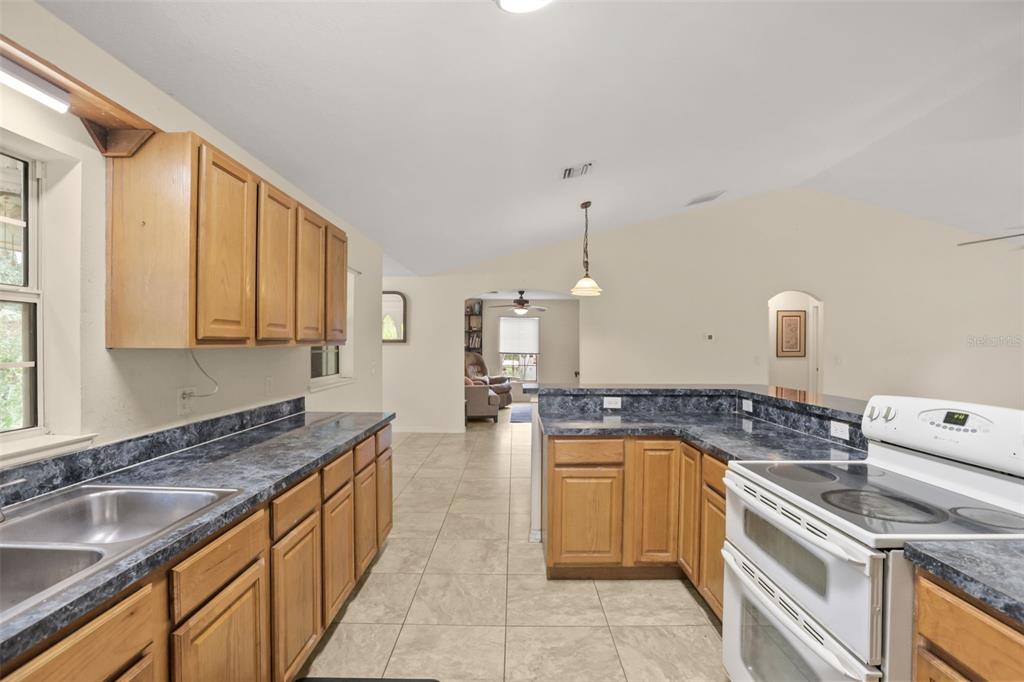 A kitchen with light wood cabinets, dark blue laminate countertops, and tile flooring — 35819 NOVA LANE, EUSTIS, FL