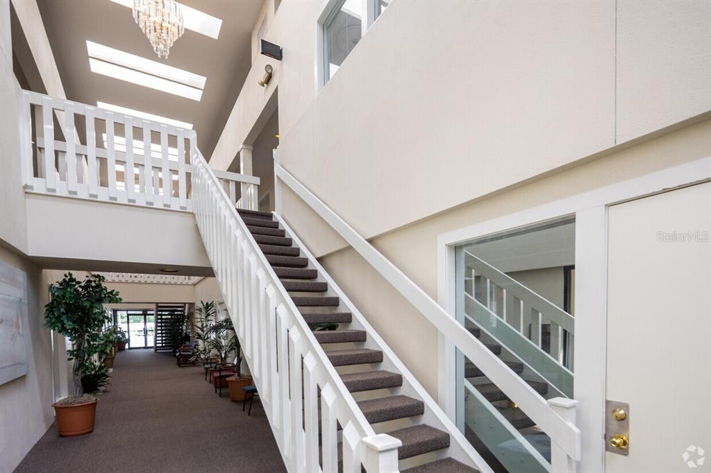 A staircase with carpeted steps and white railings leads to an upper level in a hallway — 901 DOUGLAS AVENUE UNIT 239, ALTAMONTE SPRINGS, FL
